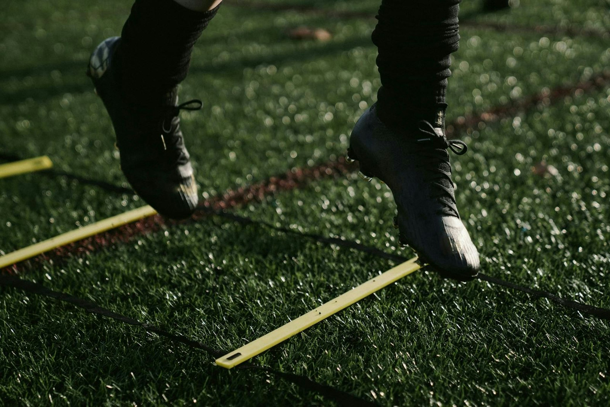 Close-up of feet in athletic shoes performing agility ladder drills on artificial turf