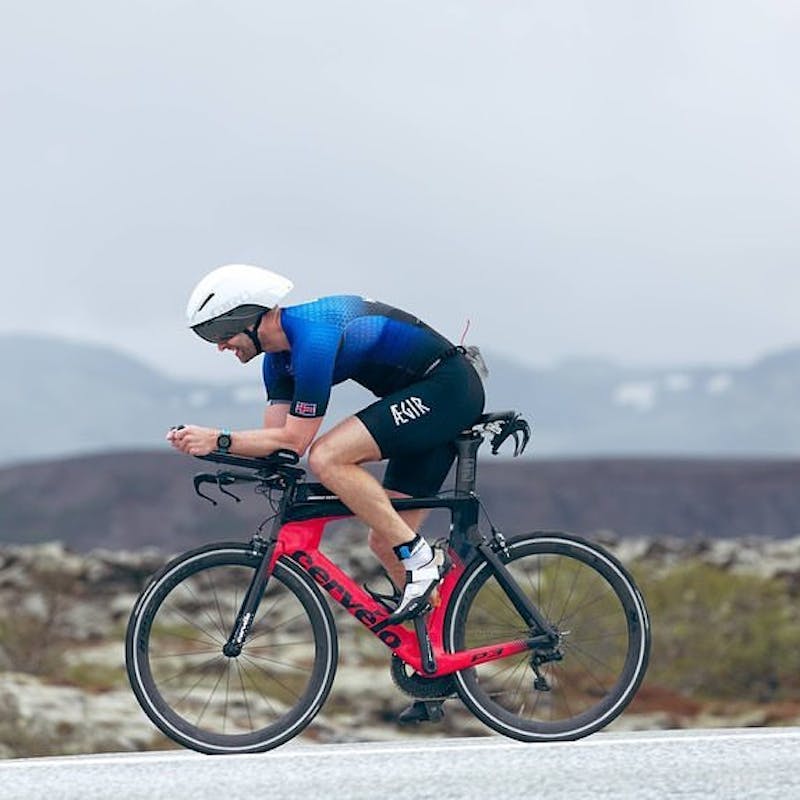 Triathlete cycling in aerodynamic position on road bike during outdoor training session