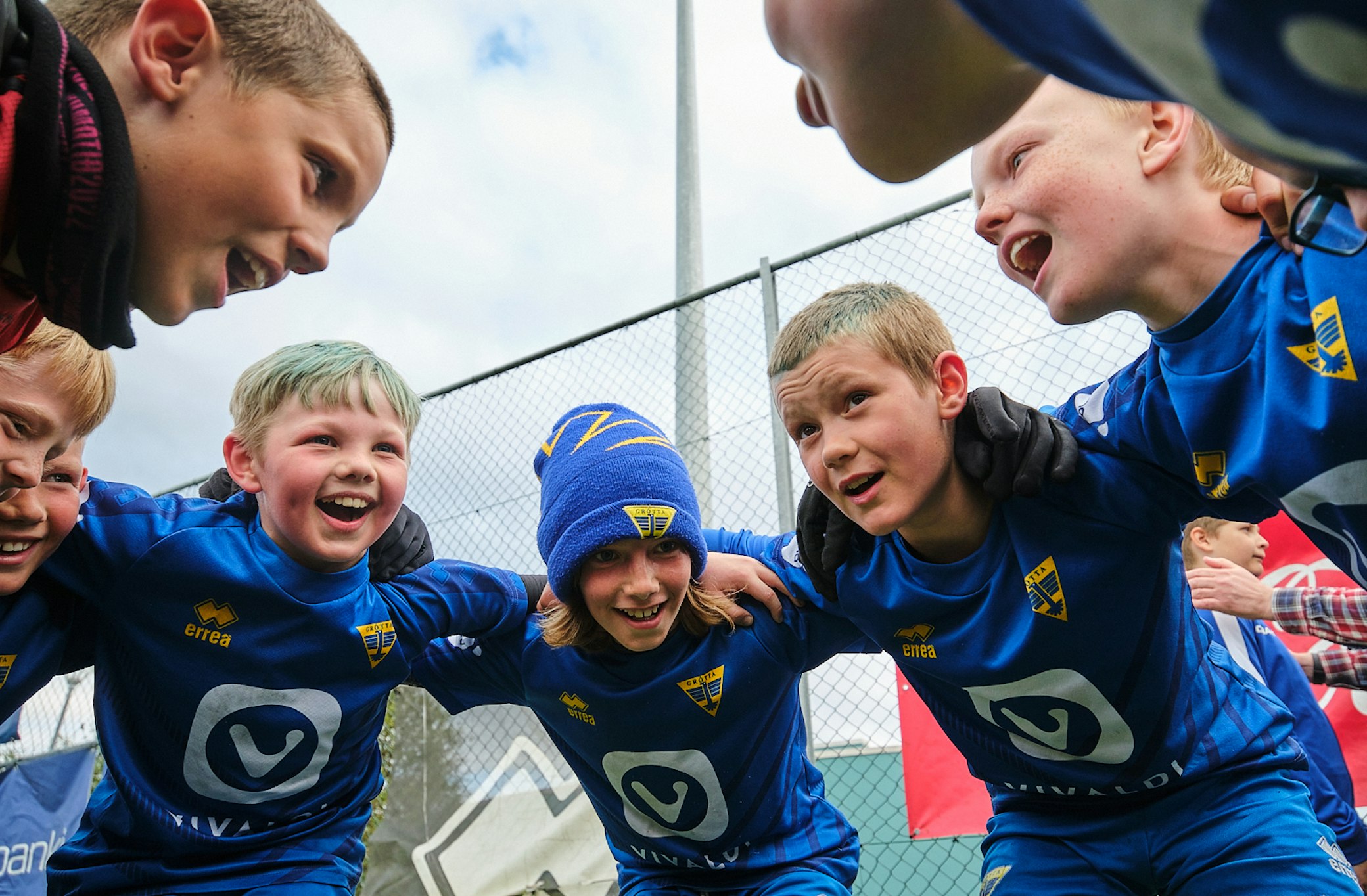 Youth football team huddle with coach before match at community sports programme