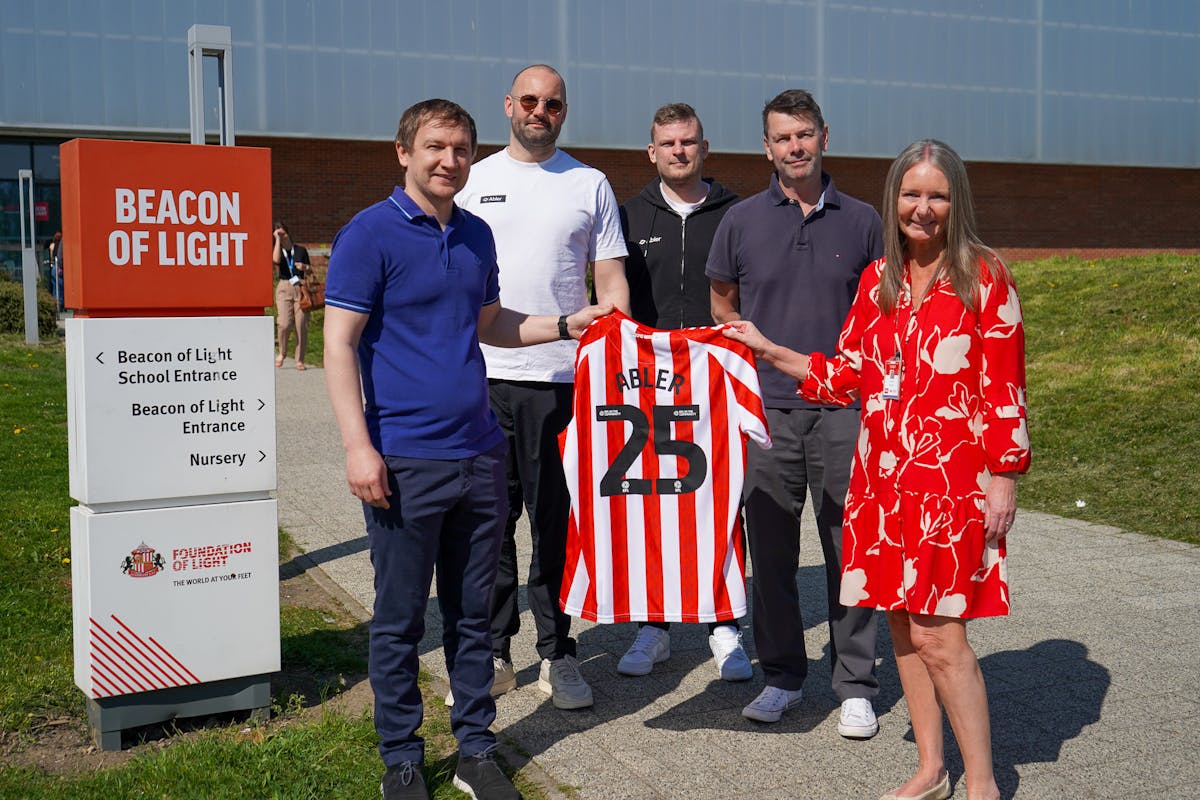 Five adults holding an Abler-sponsored Sunderland AFC jersey outside the Beacon of Light.