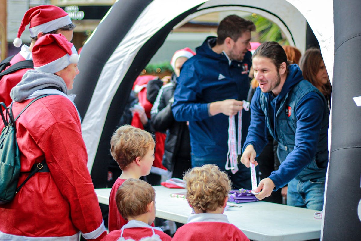 People in Santa outfits at a community event registration.
