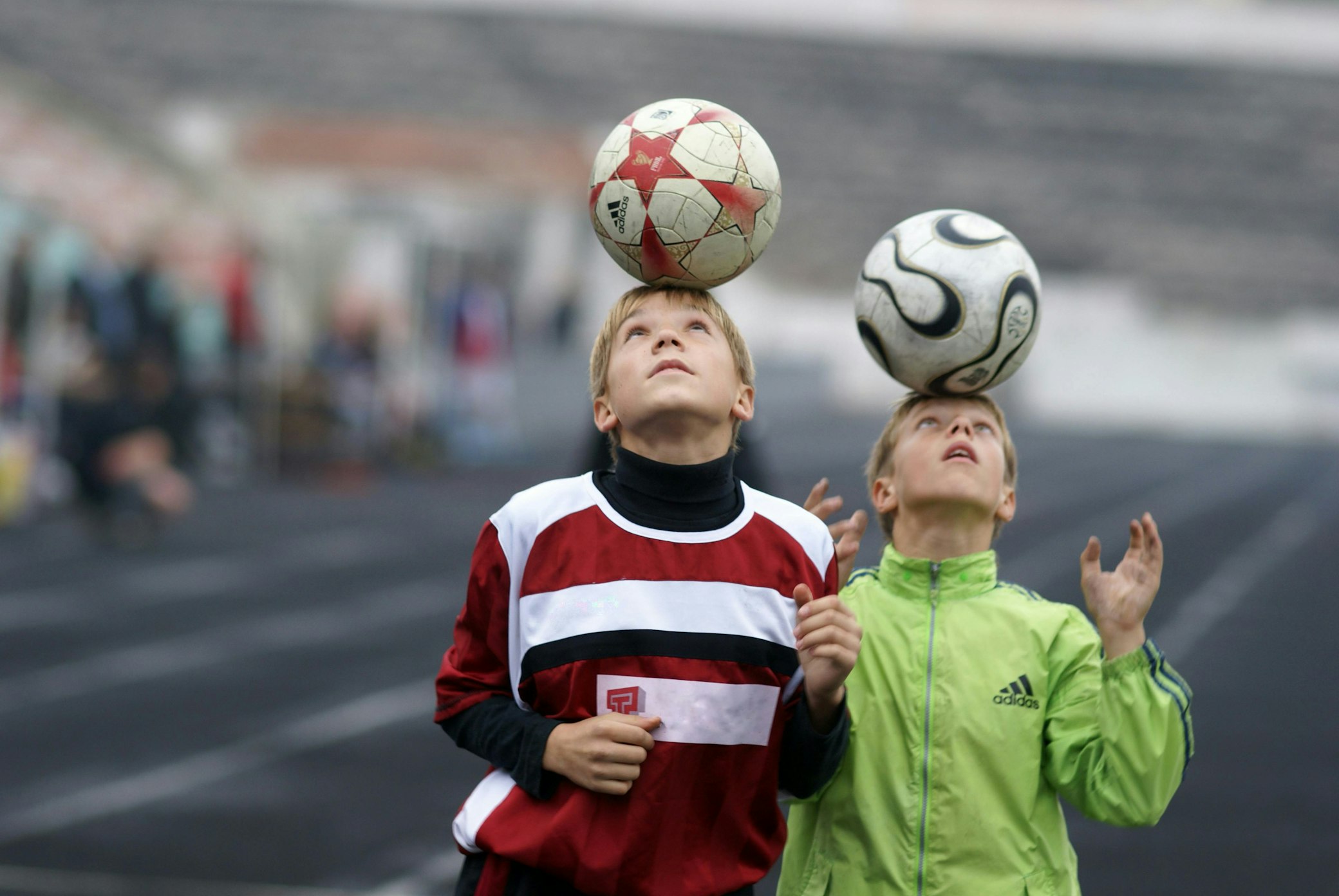 Niños equilibrando un balón de fútbol sobre la cabeza