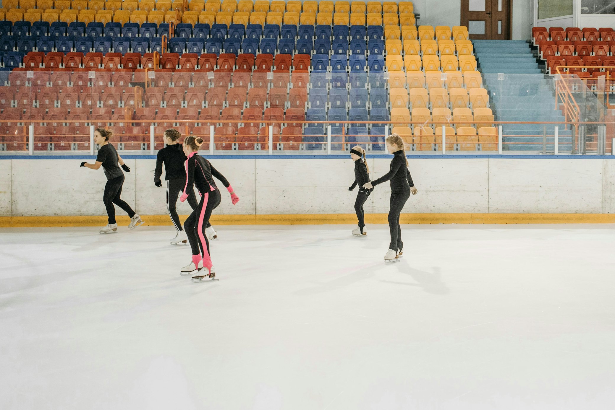 Ice figure skating members training on indoor rink at community sports facility with stadium seating