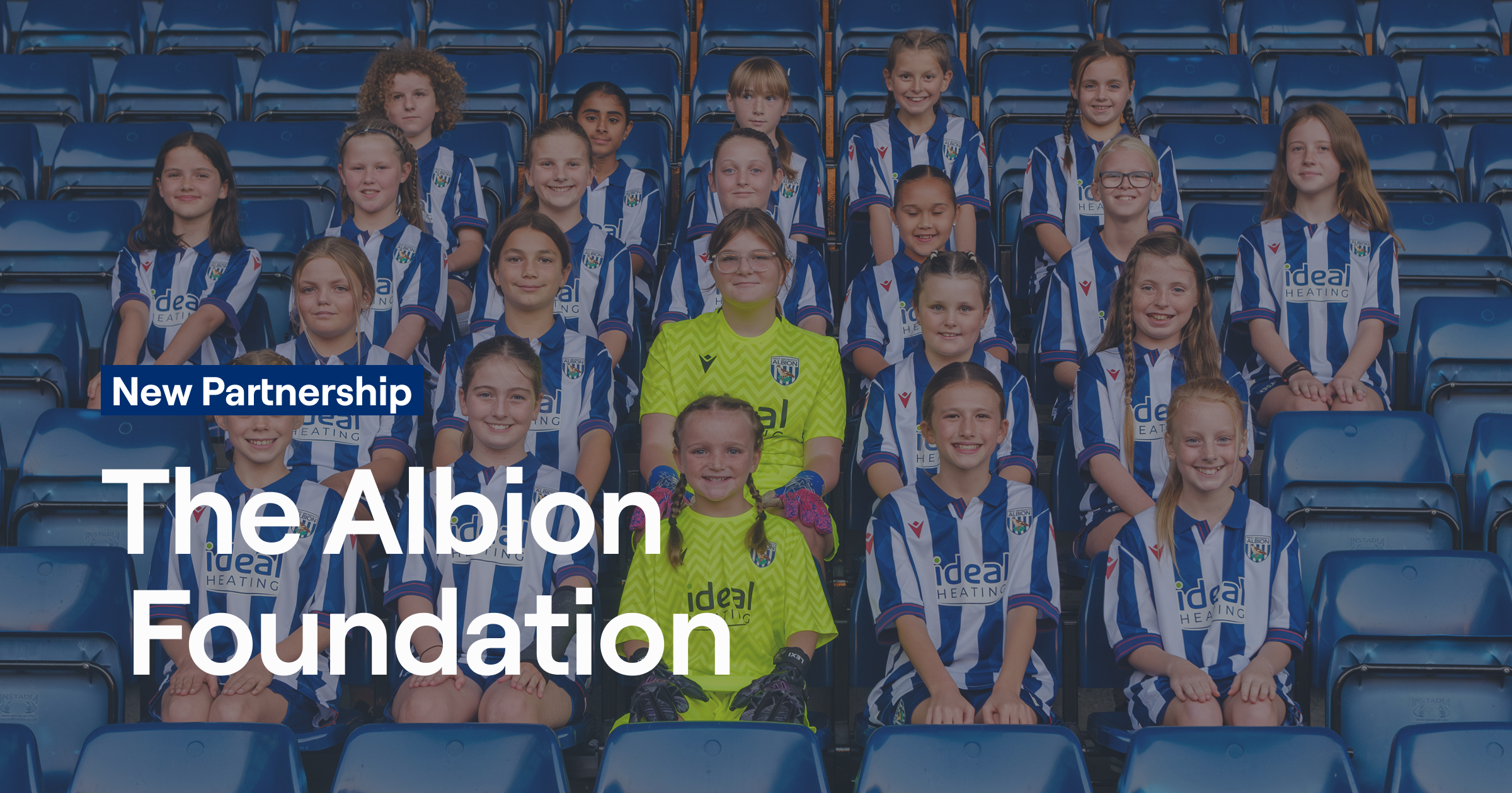 Young female football players from The Albion Foundation's programmes wearing West Bromwich Albion striped jerseys, posing together at The Hawthorns stadium, representing the Foundation's commitment to youth development and community engagement.