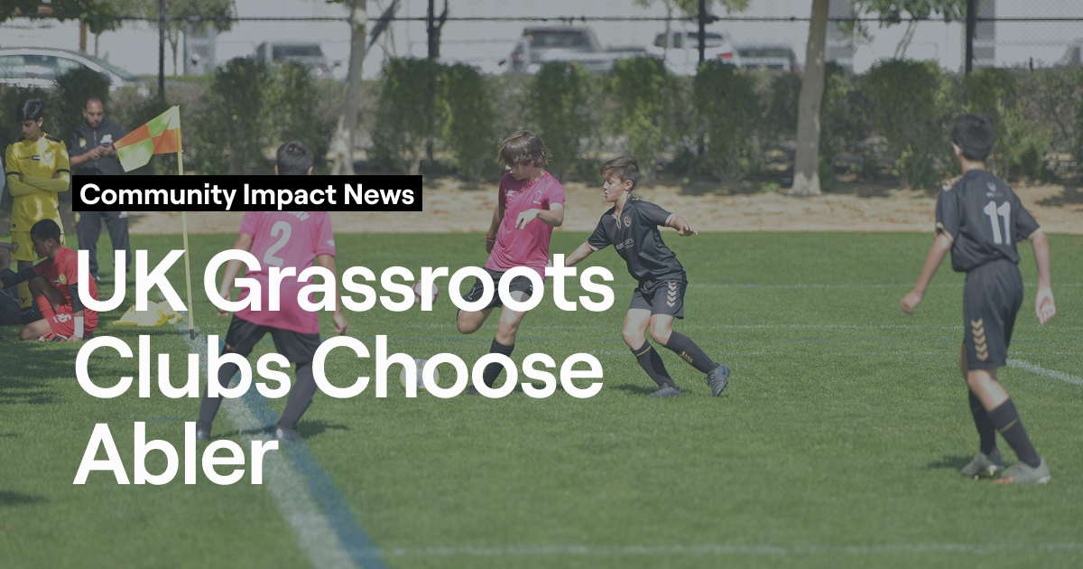 Young players competing in a grassroots football match with referee overseeing play, representing UK community clubs using Abler platform