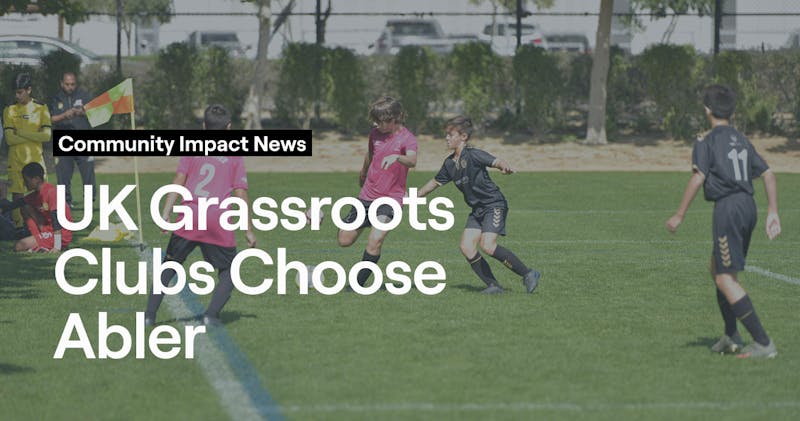 Young players competing in a grassroots football match with referee overseeing play, representing UK community clubs using Abler platform