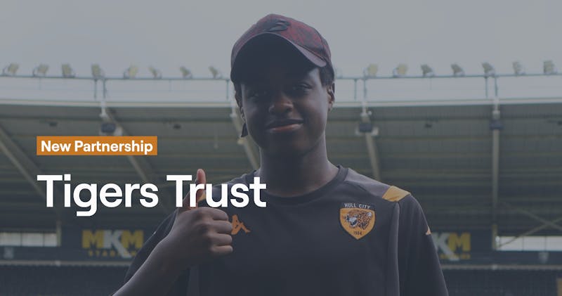 Young person wearing Hull City AFC jersey at MKM Stadium announcing new partnership between Abler and Tigers Trust