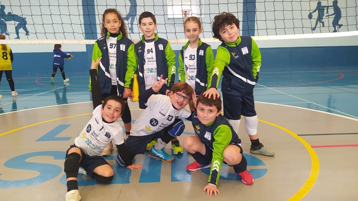 Grupo de niños del equipo juvenil de voleibol posando en la cancha, vistiendo uniformes azul marino con verde neón y blanco, con el logo de Textil Santanderina