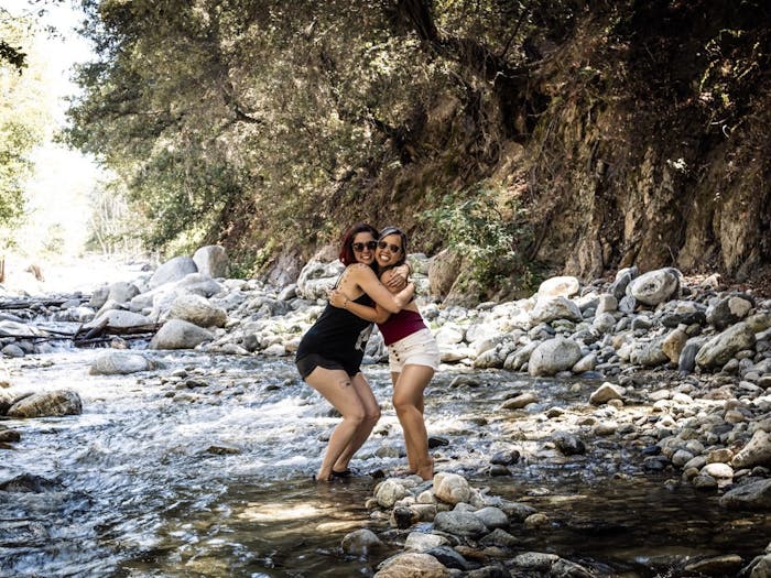 Danielle and Mimi standing on rocks in a running mountain stream hugging 