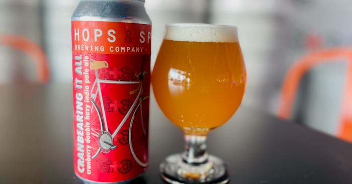 A pint and tall can of Hops & Spokes most popular brew - Cranberry Double Hazy IPA called CranBEARING it All
