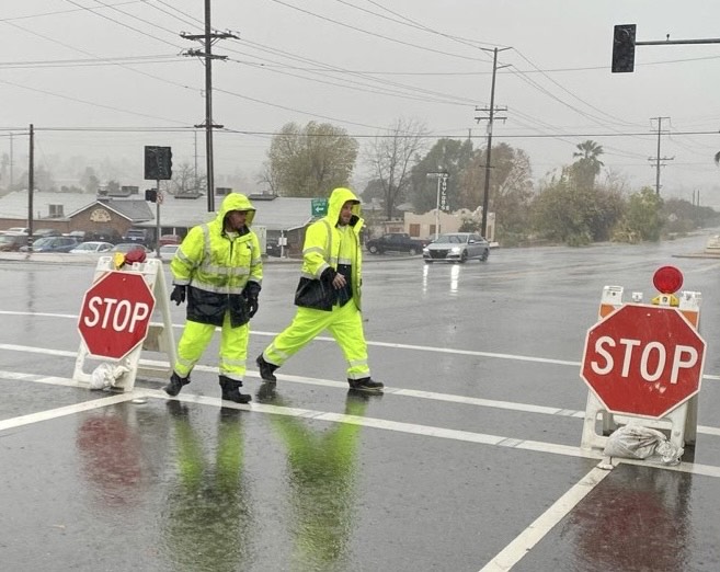 City of Redlands Teamster Employees putting temporary stop signs up in a dark intersection. 