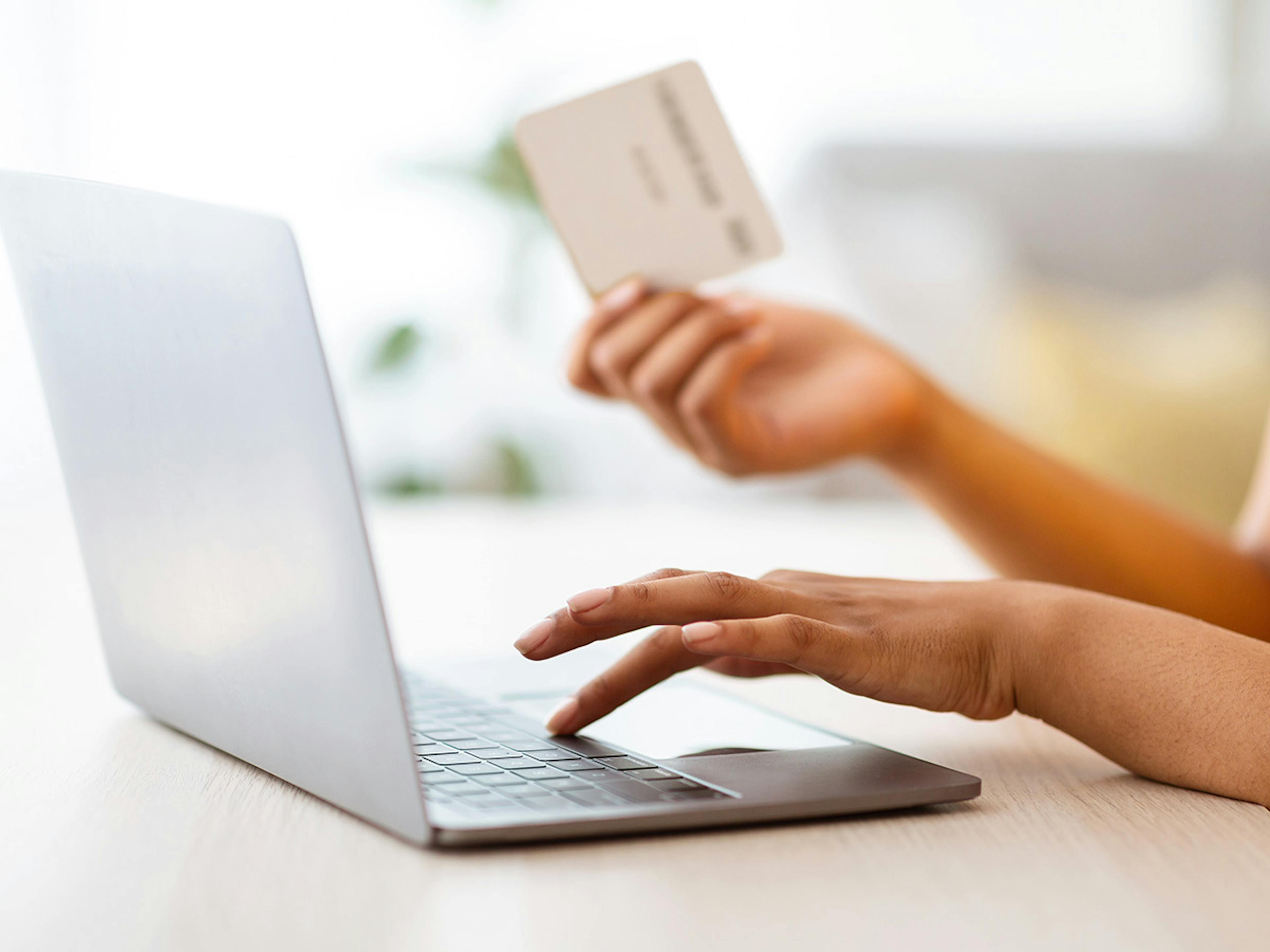 Woman holding gift card by computer