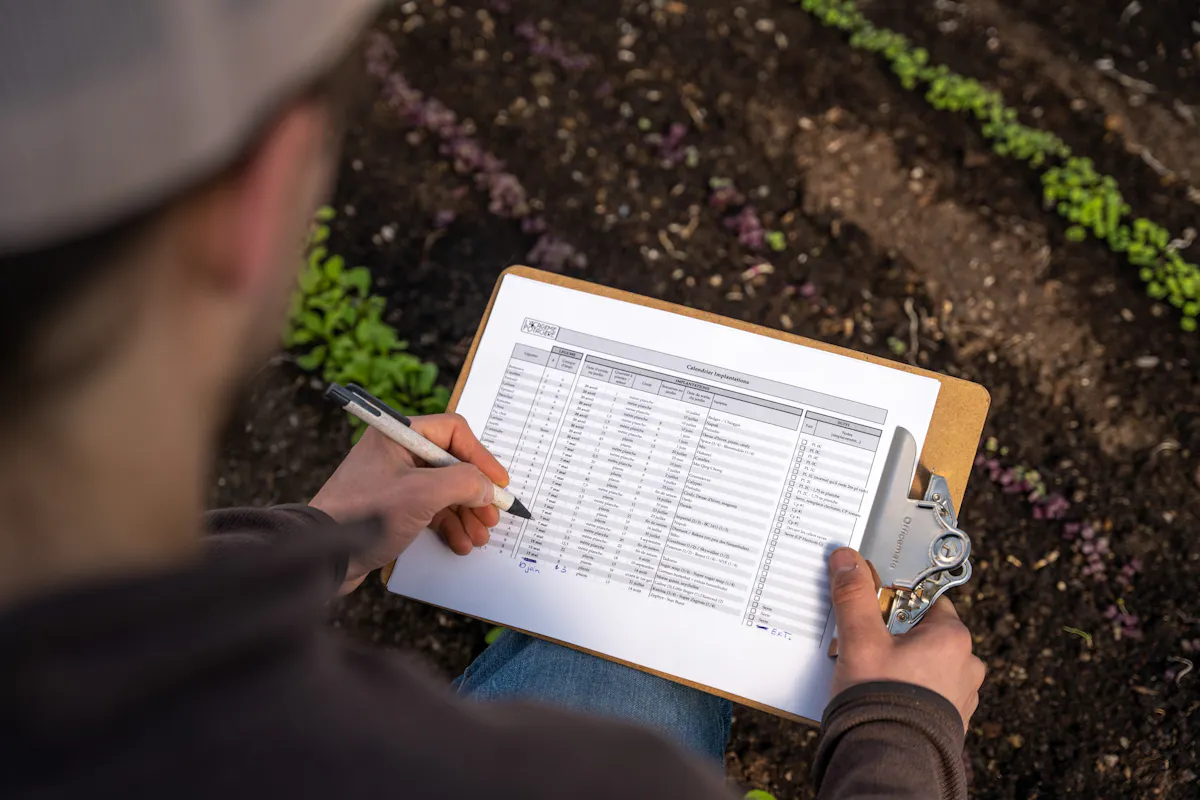 Dany qui prend des notes au potager pour mieux planifier la prochaine saison