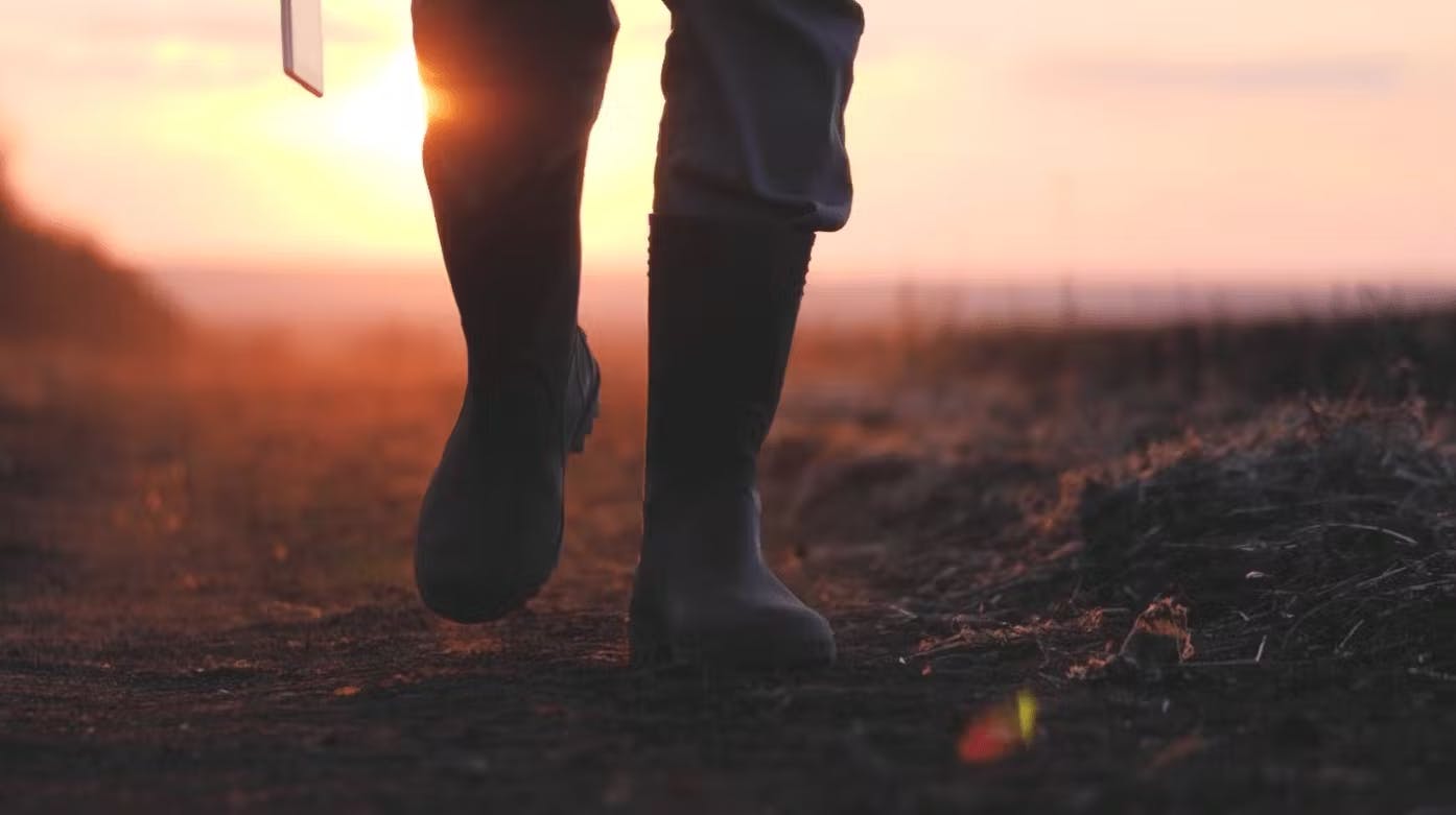 Farmer wearing rubber boots walking on soil