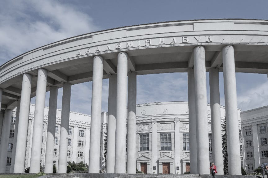A white circular building with towering pillars and greek lettering across the front facade
