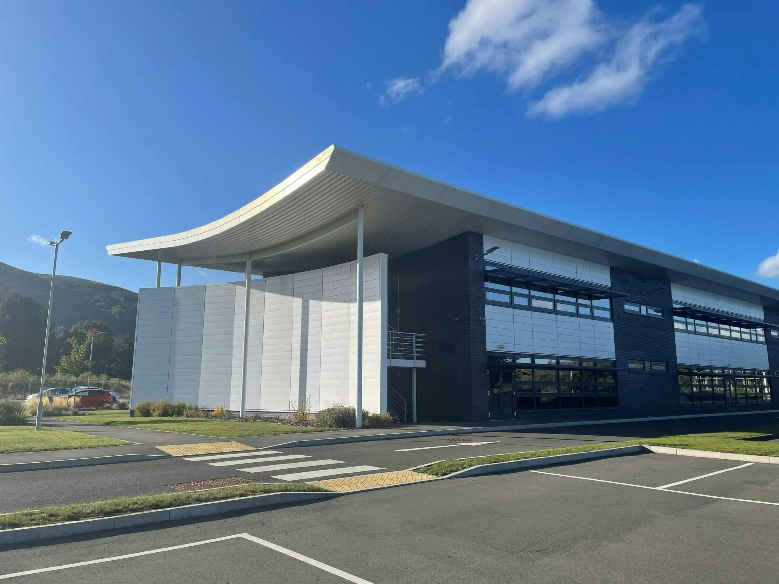 A photo of the exterior of the UK Center of Excellence from the parking lot, with a wide blue sky above the large building.