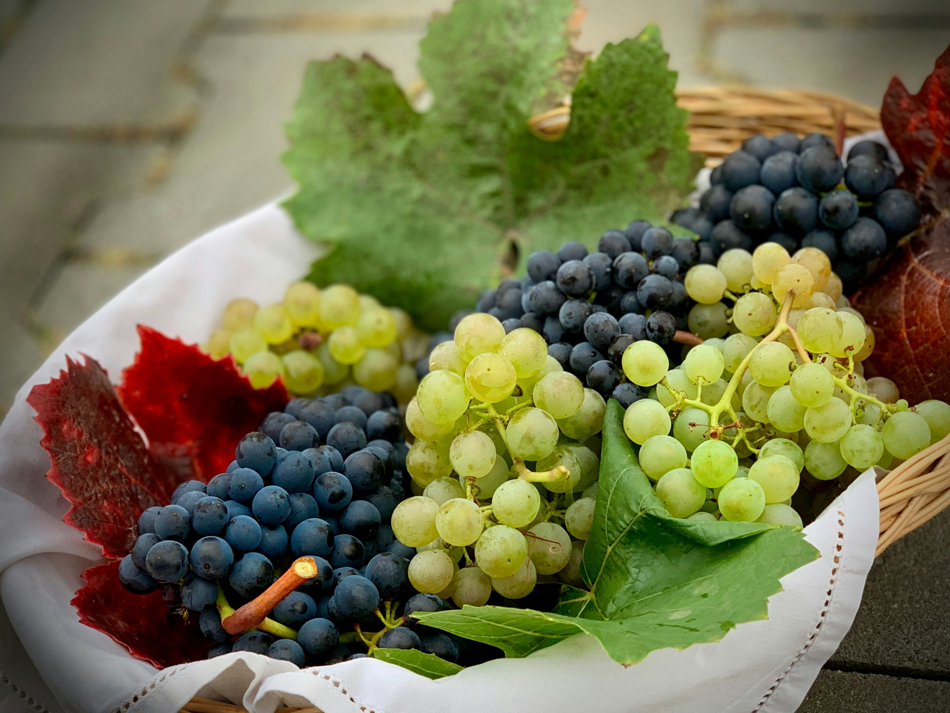 A basket filled with both green and dark purple grapes.