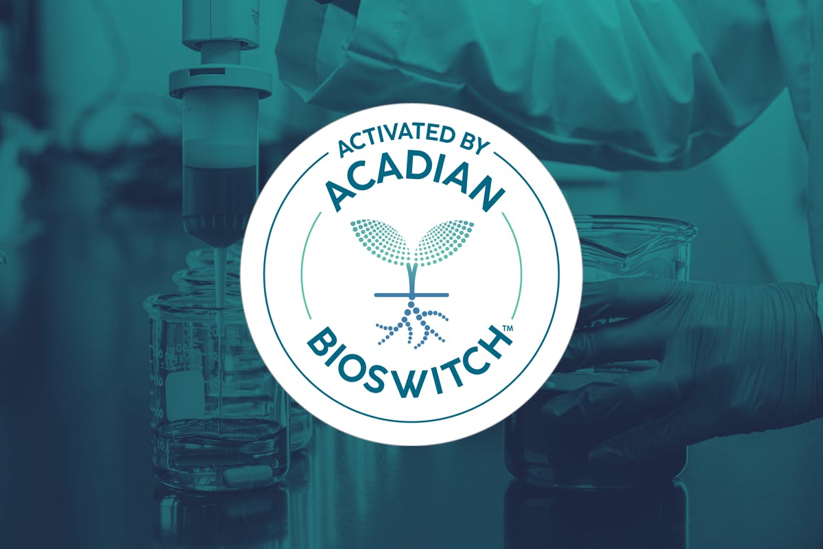 A white logo noting "Activated by Acadian Bioswitch" on top of a background image of a scientist with beakers