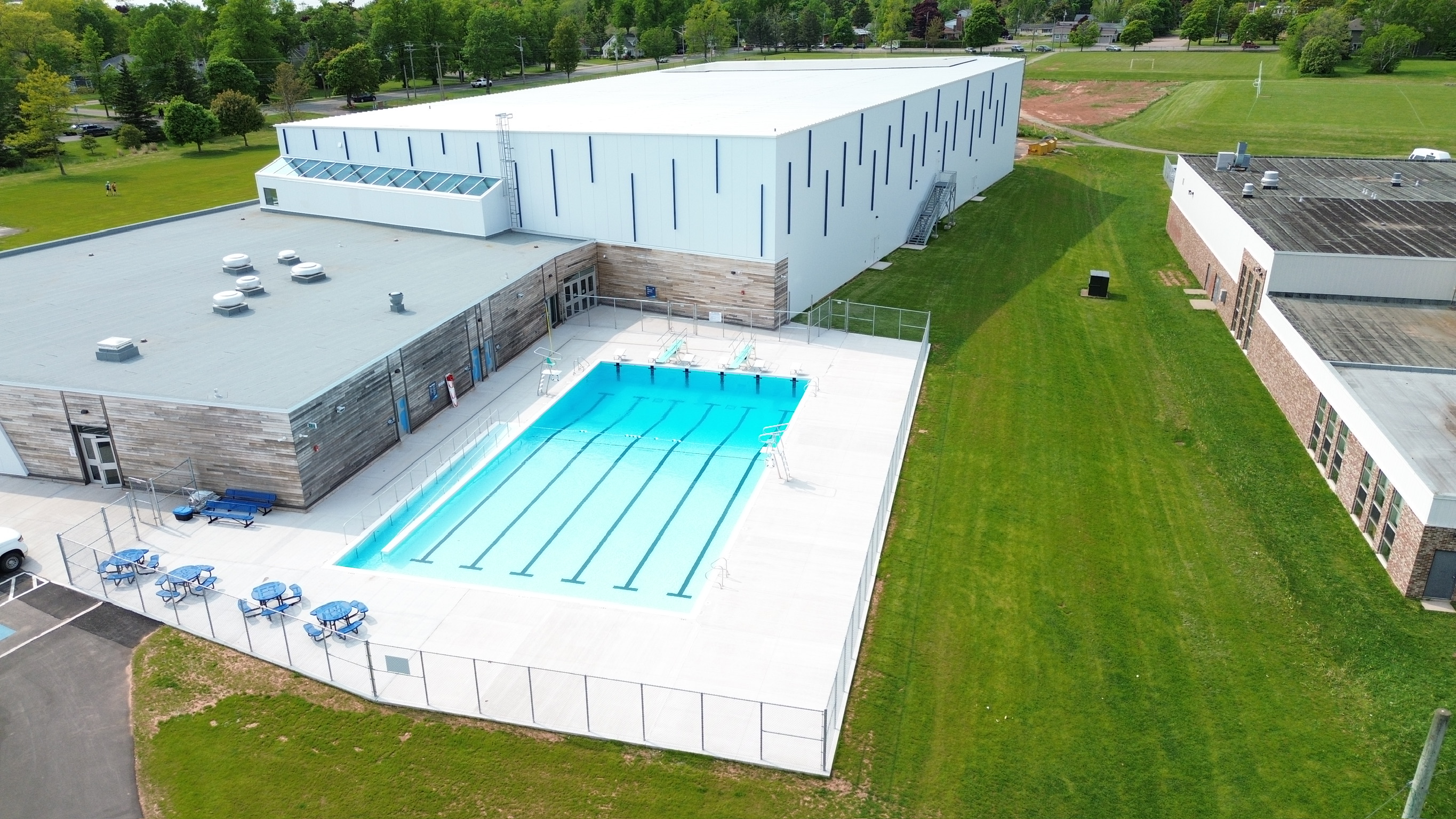 A drone photo of an outdoor pool on a sunny day. It's bright blue with ...