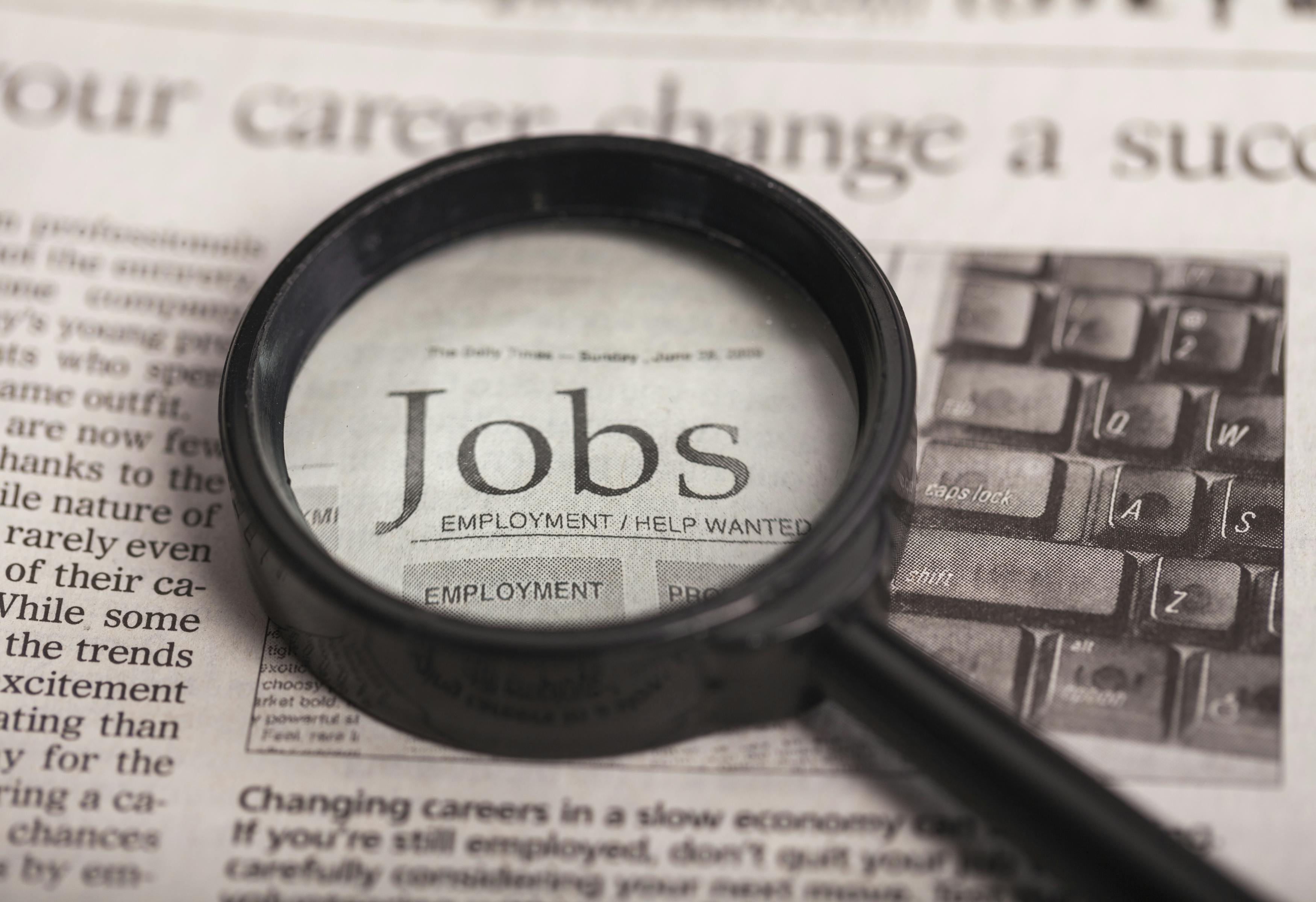 magnifying glass on a newspaper over the word Jobs