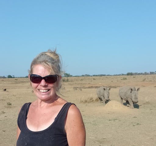 A female ACE volunteer posing in front of two rhinos