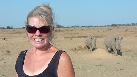A female ACE volunteer posing in front of two rhinos