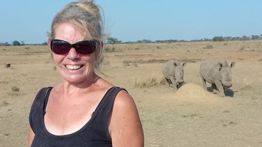A female ACE volunteer posing in front of two rhinos