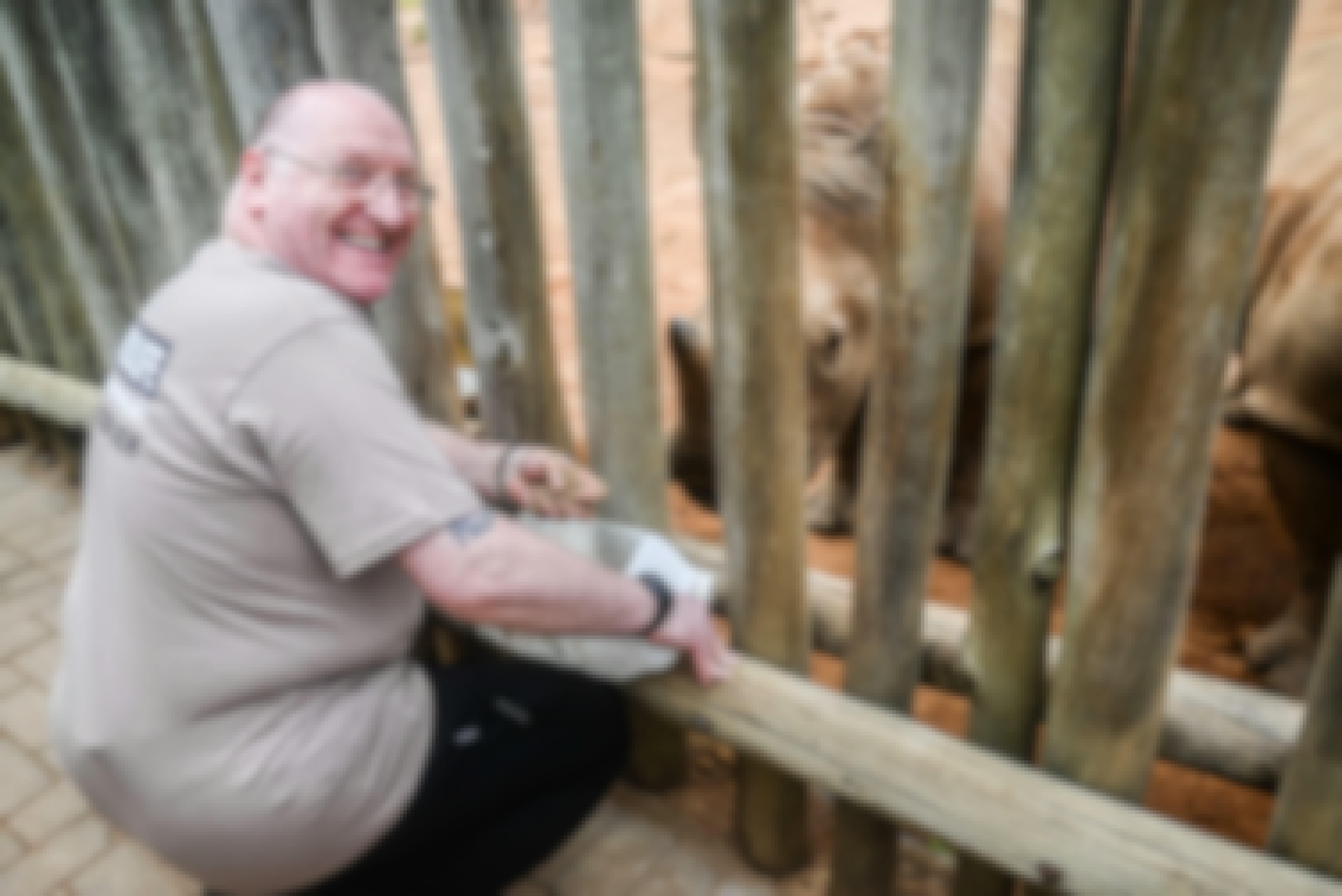 Male volunteer smiling at the camera as he feed a rhino, Care for Wild Africa