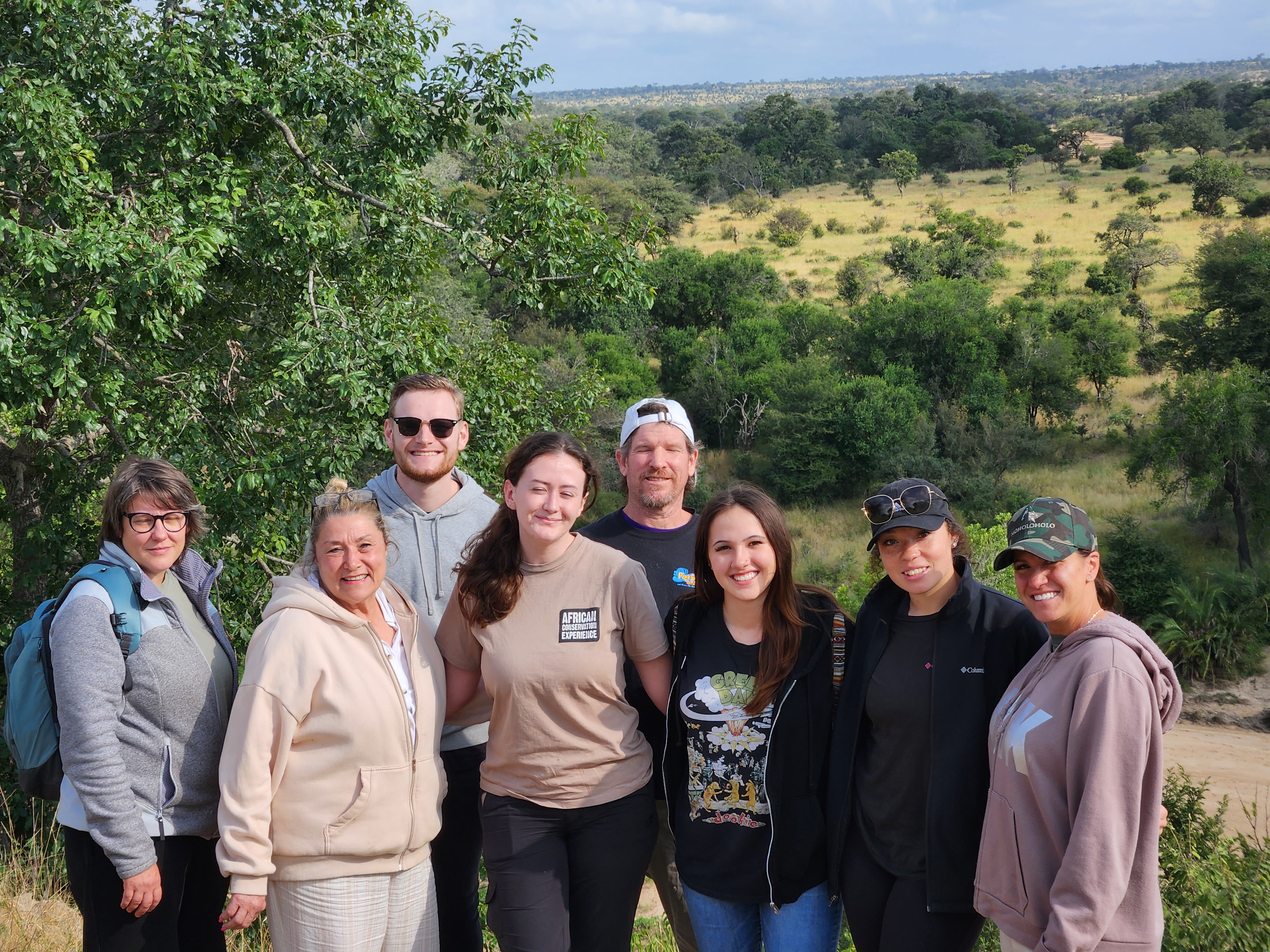 Vanessa and Caydence: A group of volunteers stood in front of a plain
