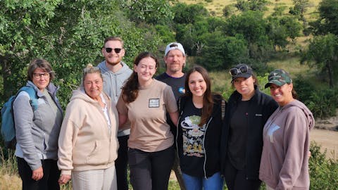Vanessa and Caydence: A group of volunteers stood in front of a plain