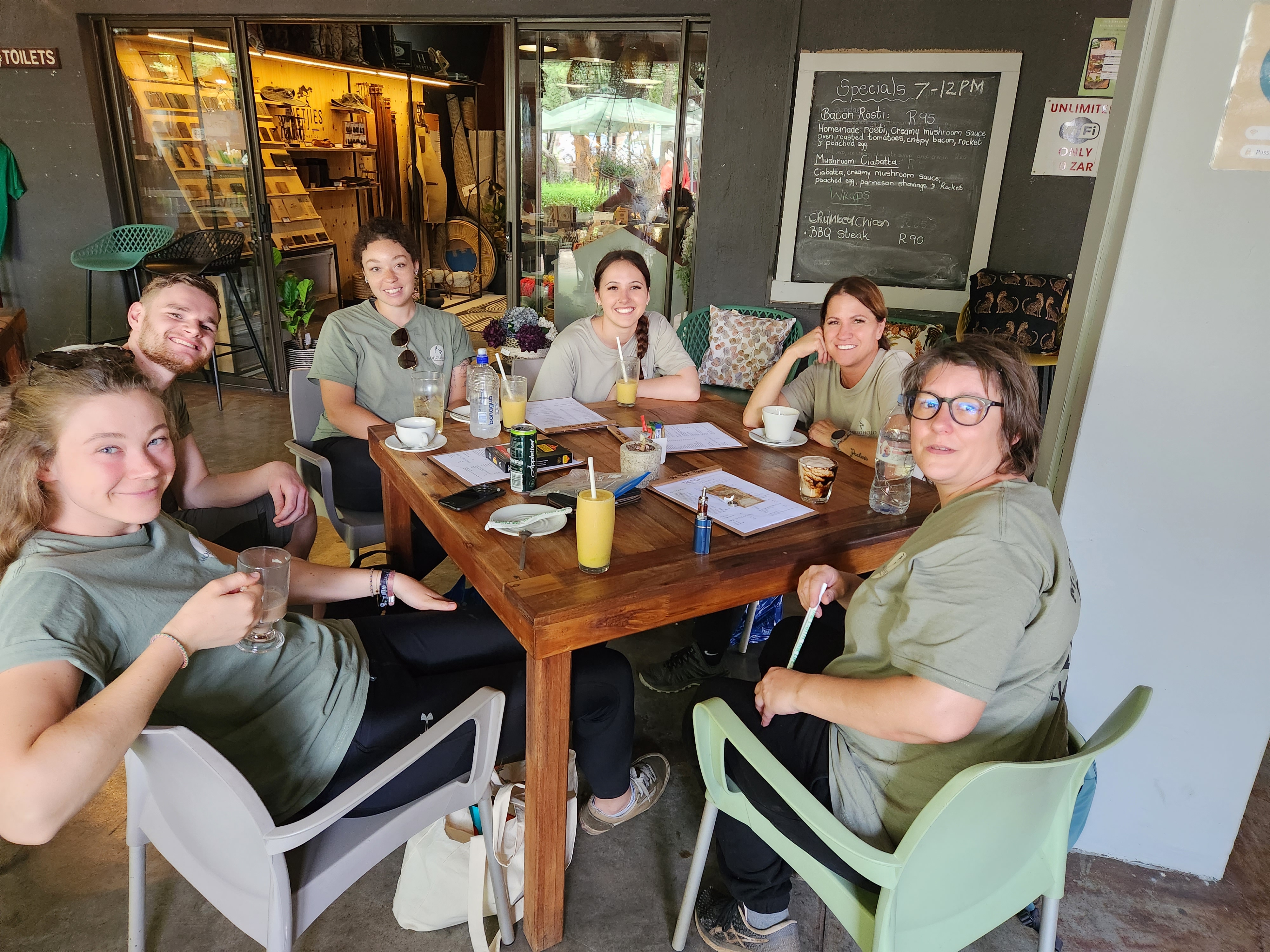 Vanessa and Caydence: A group of volunteers sit around a table at a cafe