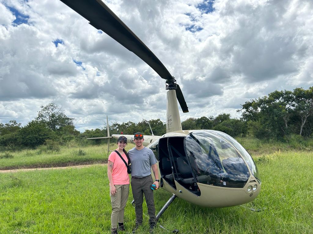 A couple pose in front of a helicopter