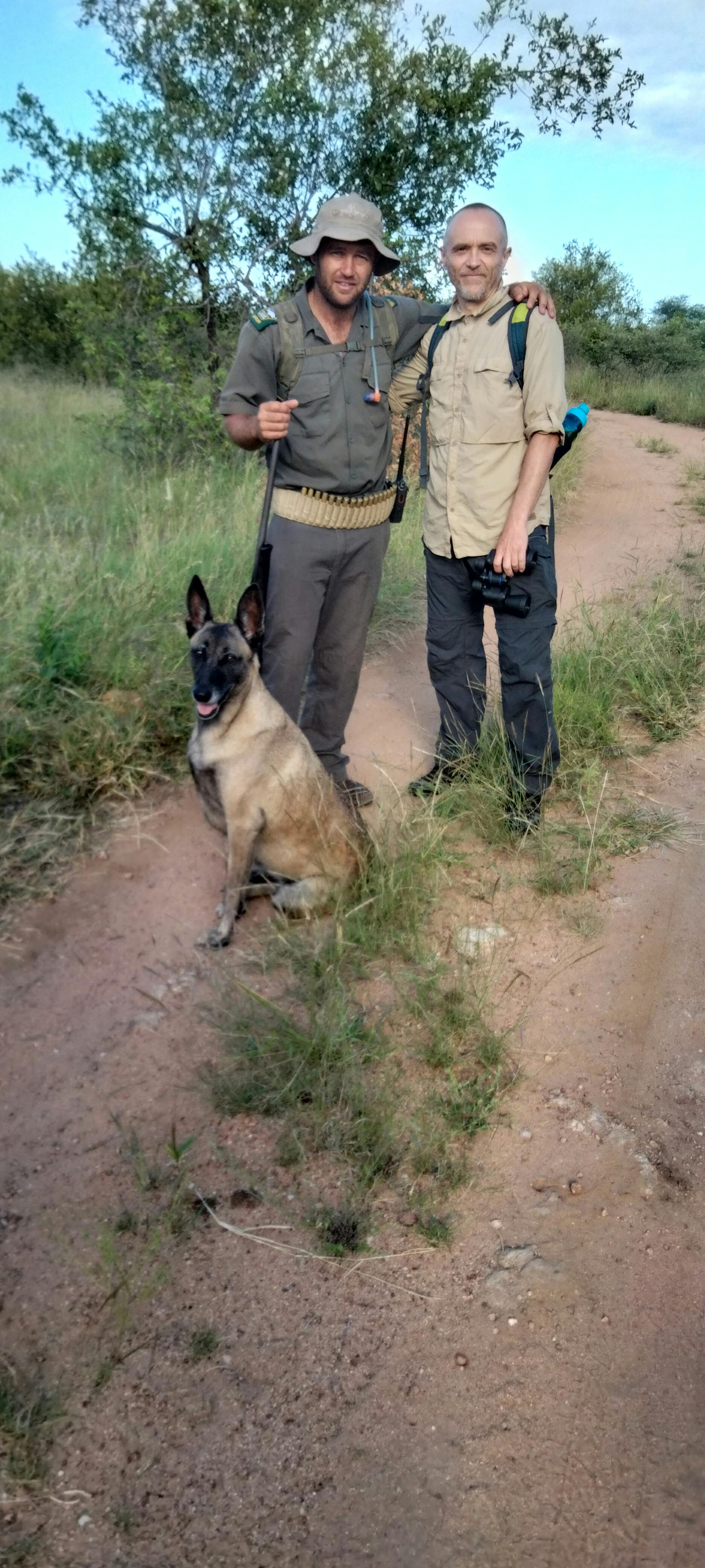 Two men and a dog pose for the camera 