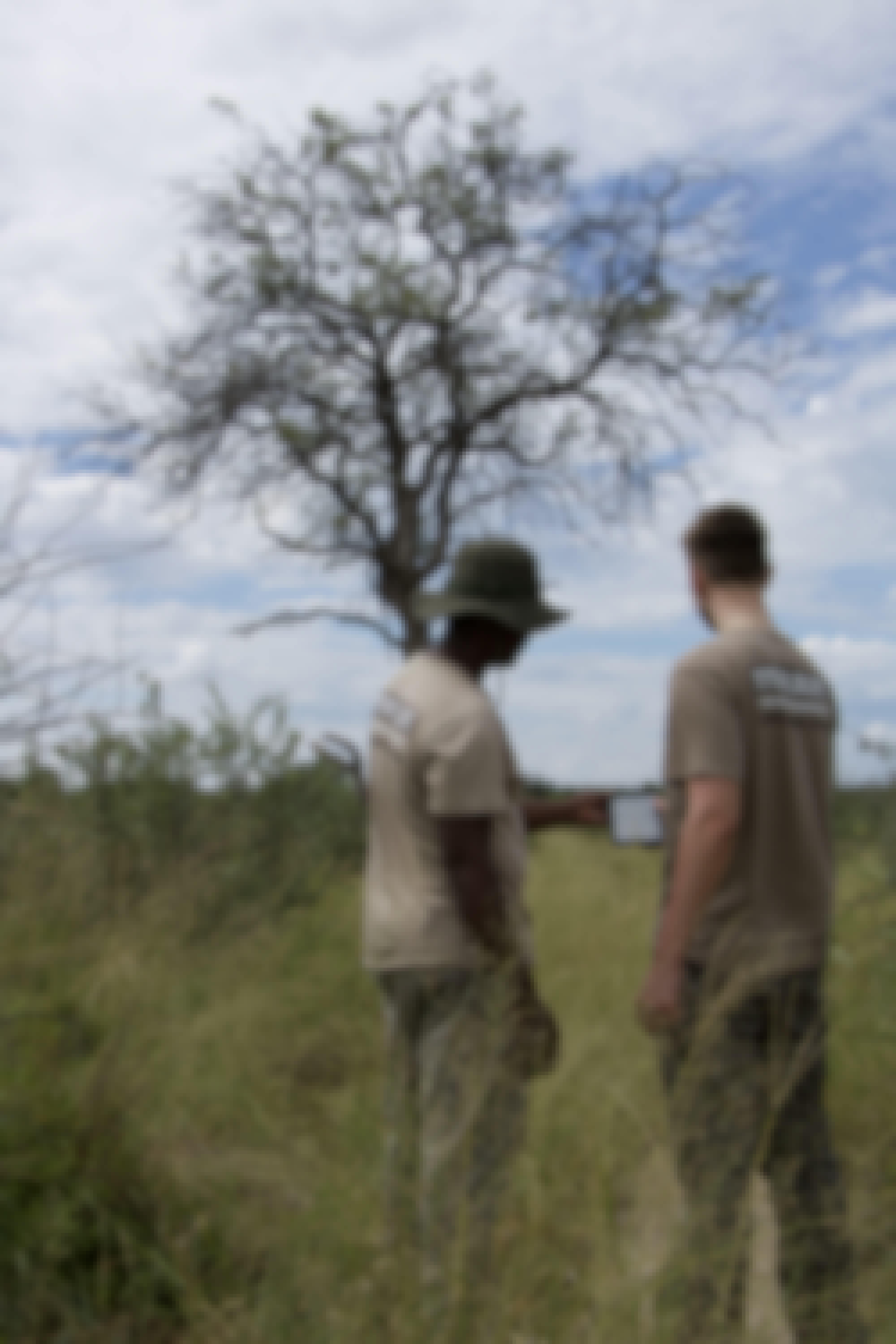 Two males looking at a tablet in the bush
