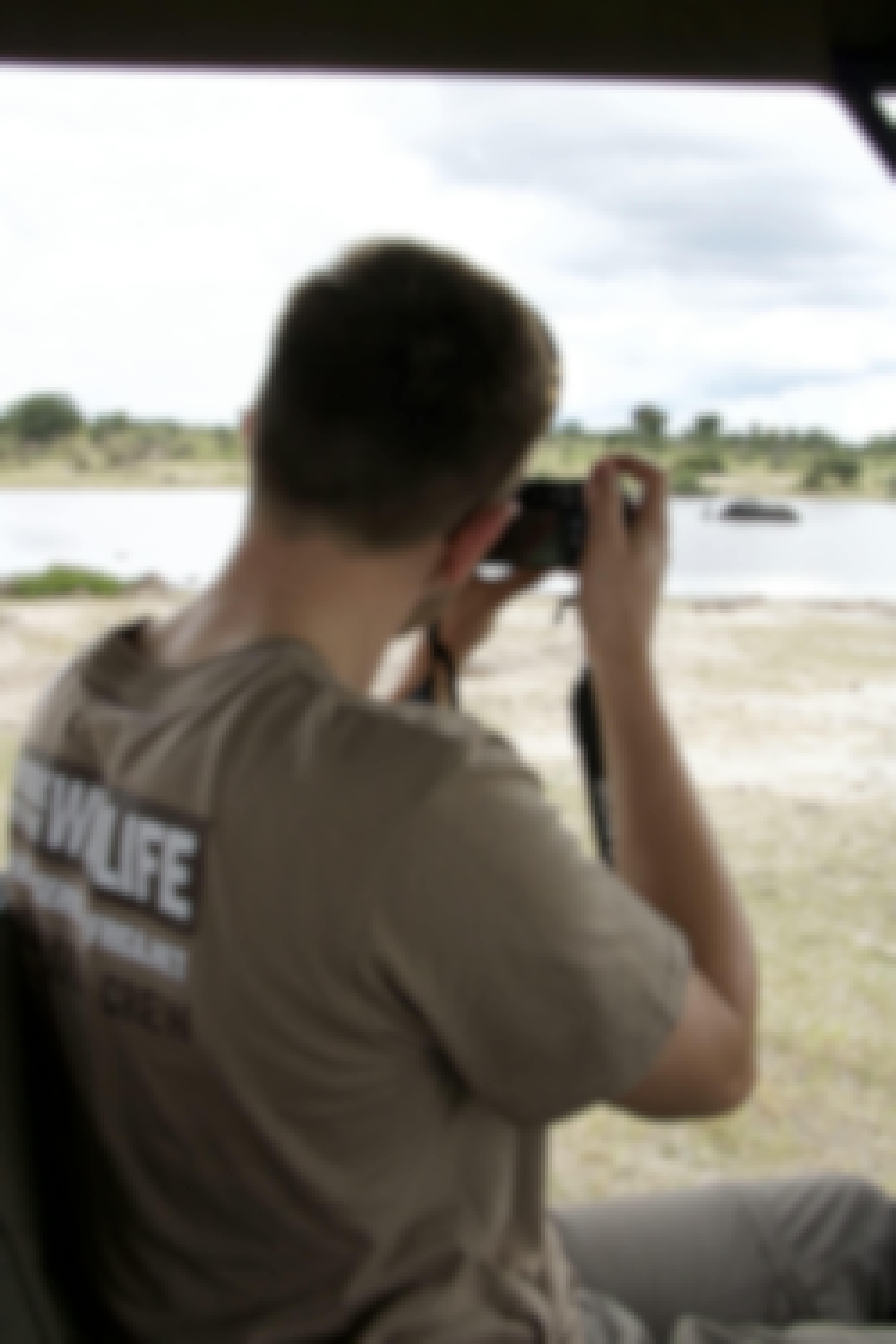 A male student takes photos of an elephant in the water