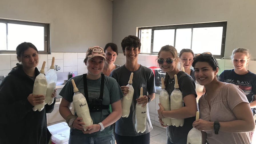 Nina Kubicek: group posing with bottles of formula for rhinos