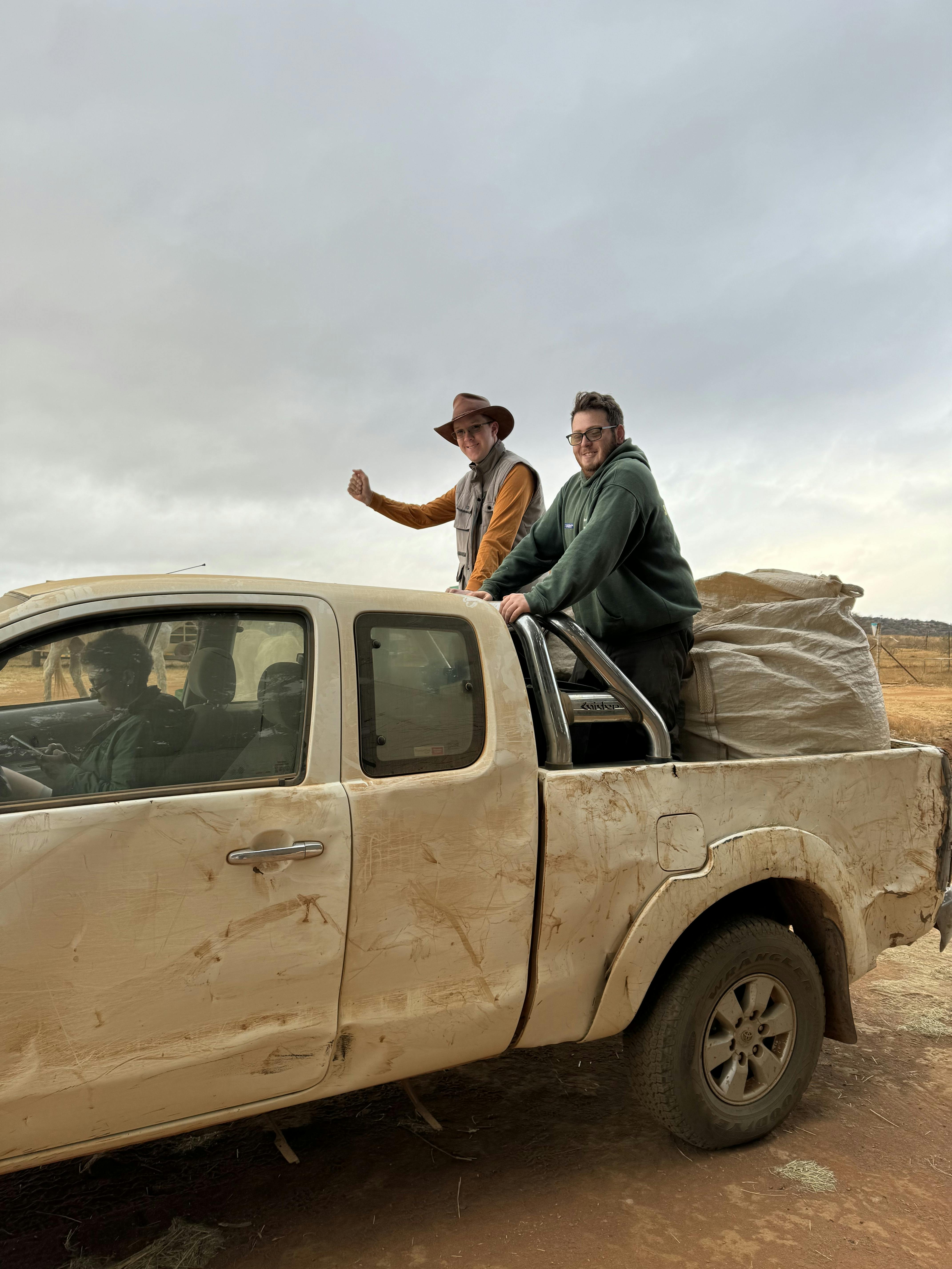 Amanda Thompson: two male volunteers smiling on the back of the truck 