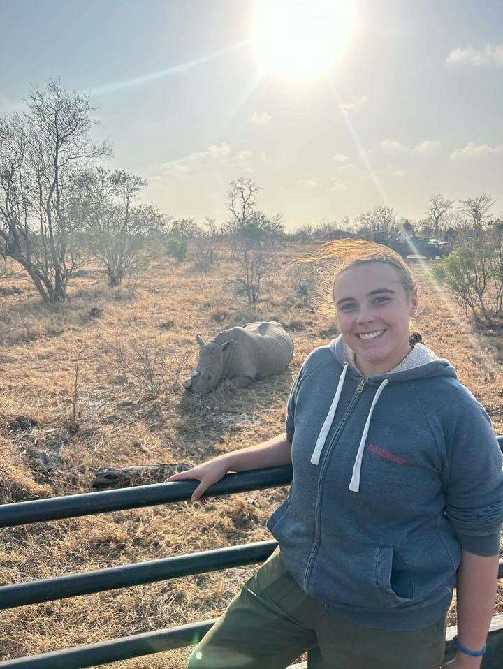 Caitlin Bayliss: female volunteer posing near a rhino