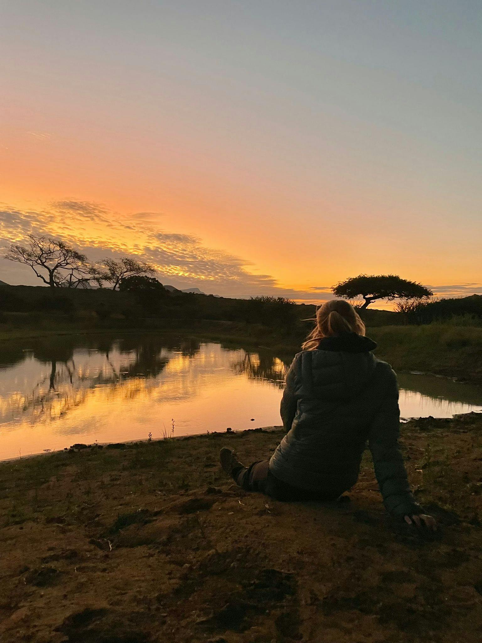 ACE volunteer relaxing beside the water while the sun sets