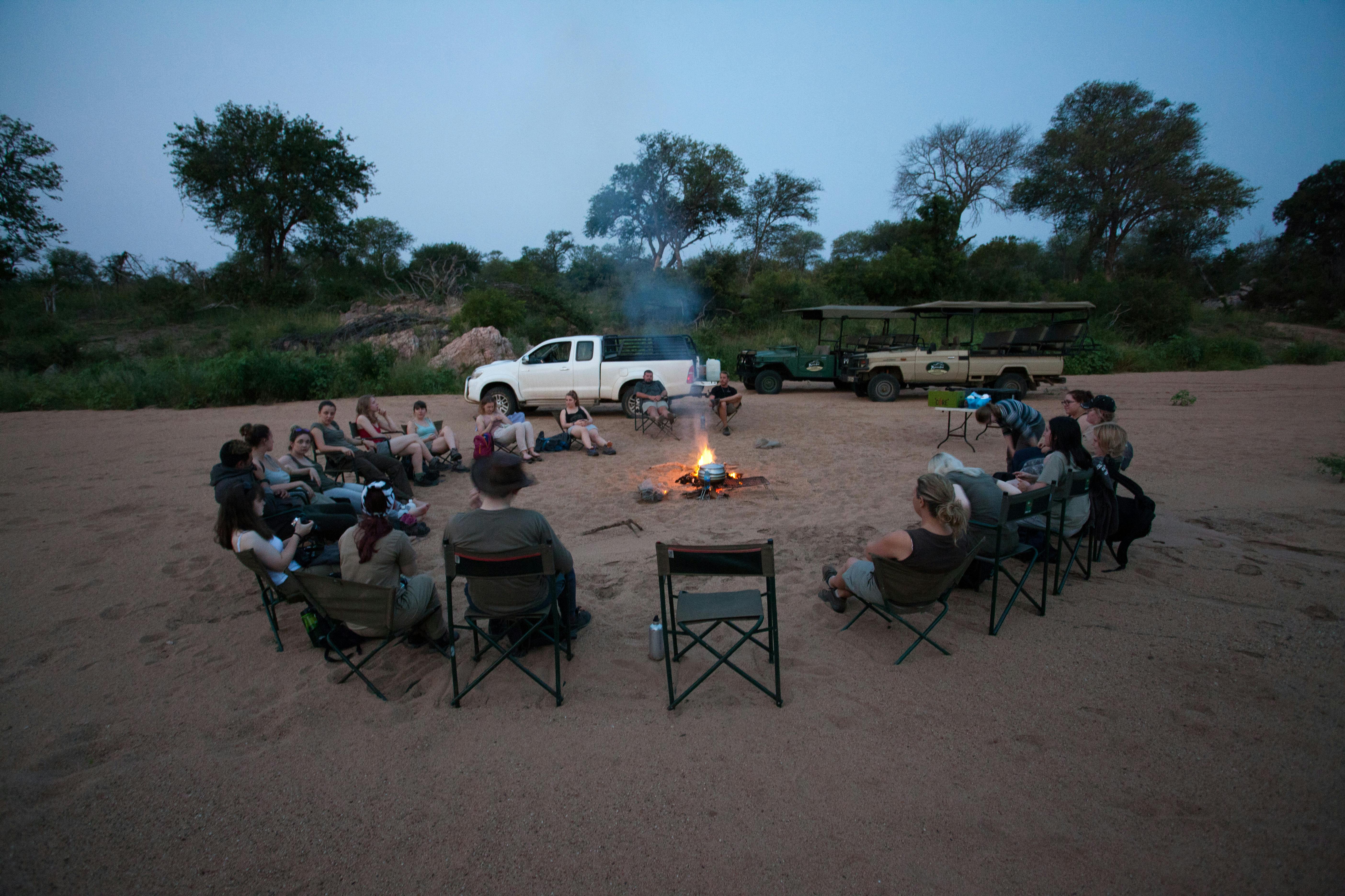 School group relaxing around the campfire