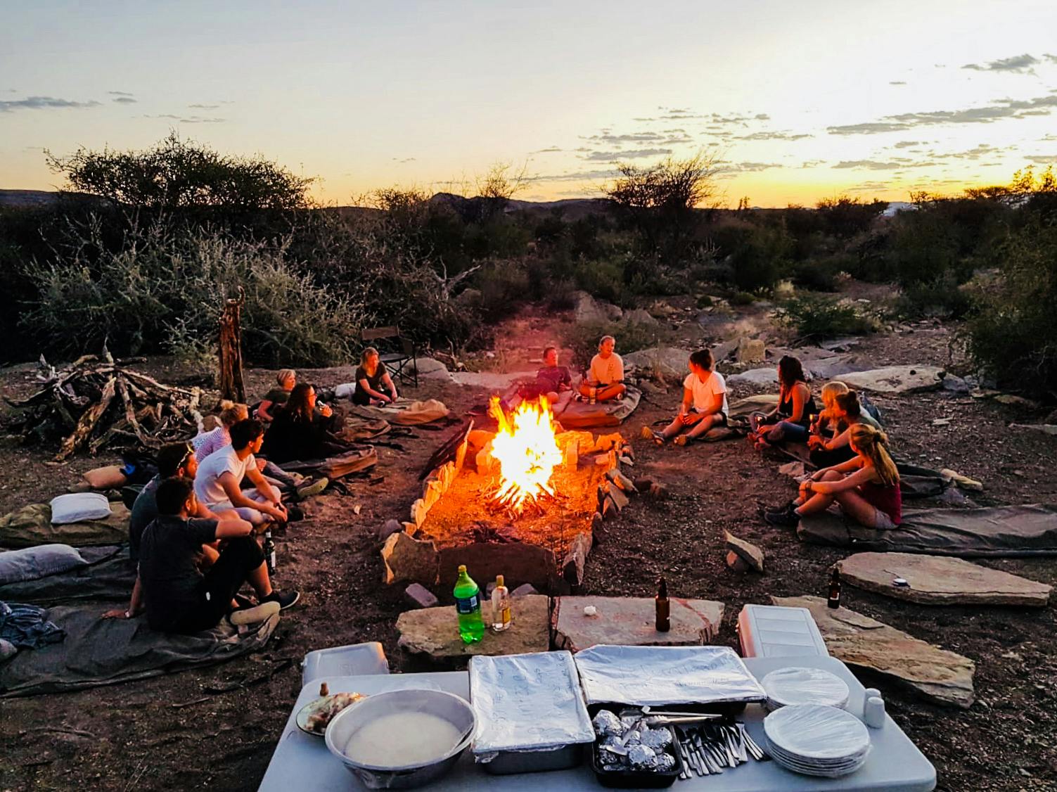 Student group relaxing around the fire at Naankuse