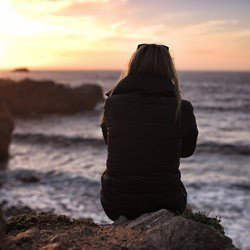 A woman enjoying a sunset by the coast alone