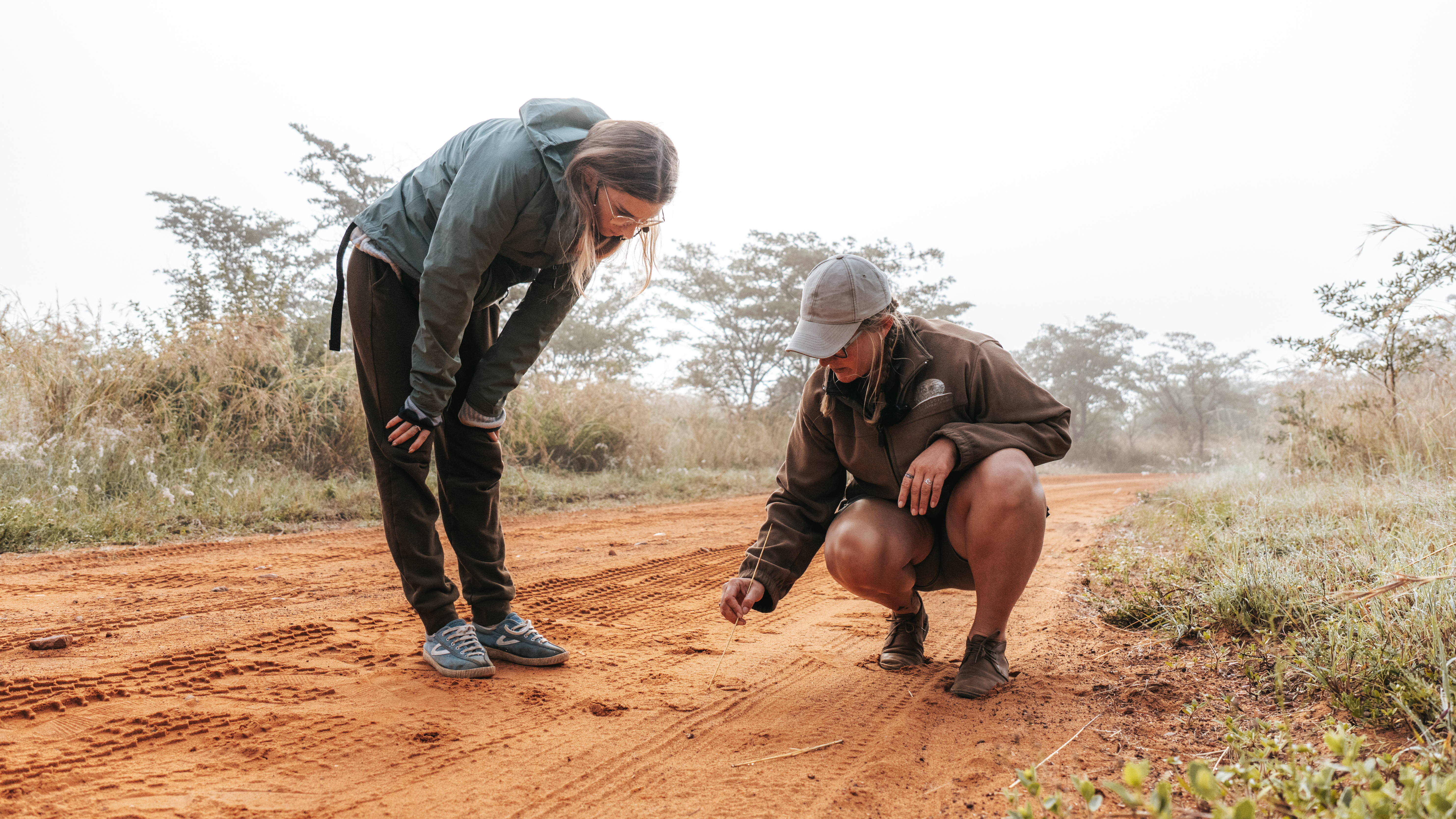 Rhino Conservation Experience - volunteer and tracker looking at rhino tracks 