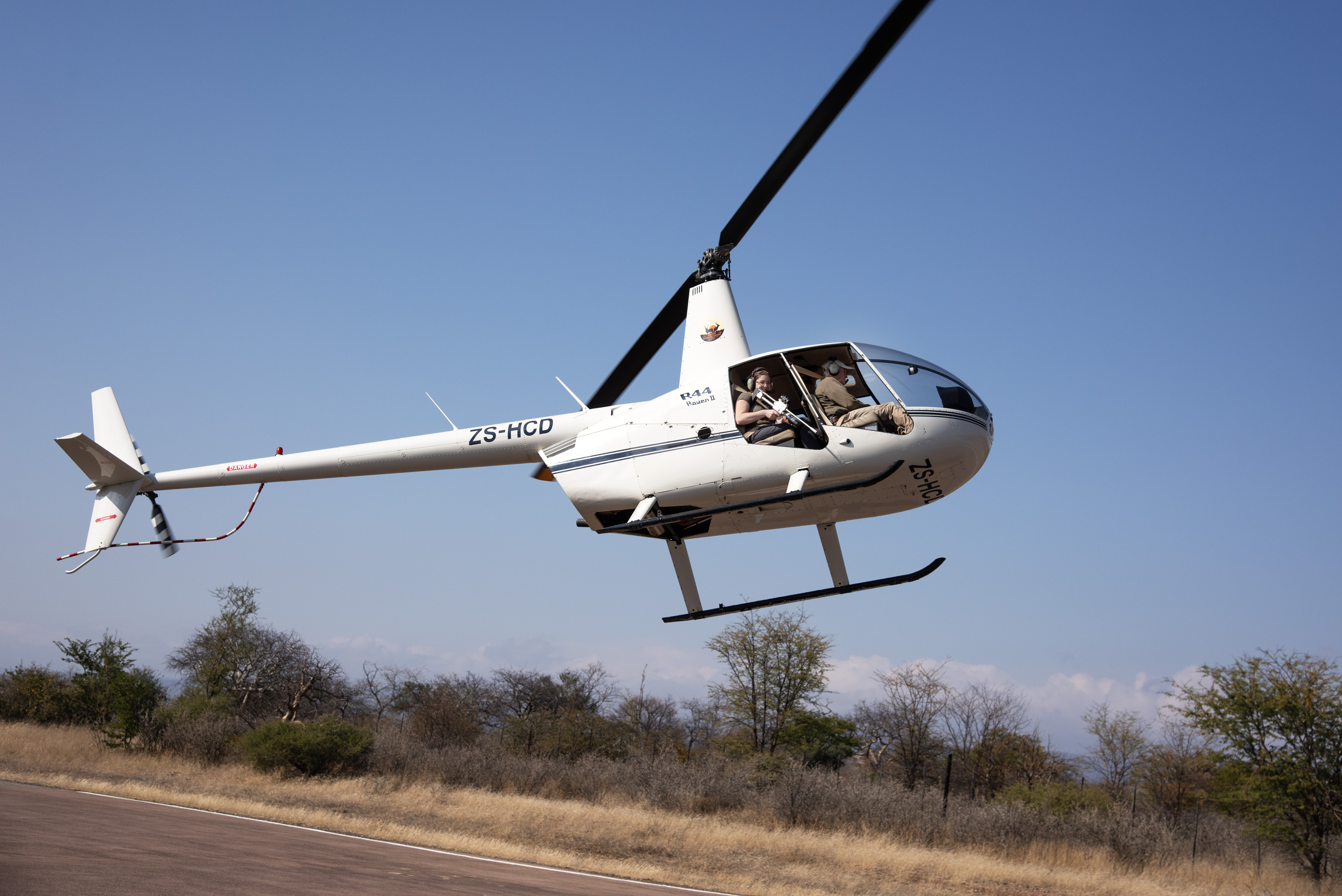 The Savannah Veterinary Explorer - volunteer with dart gun in a helicopter