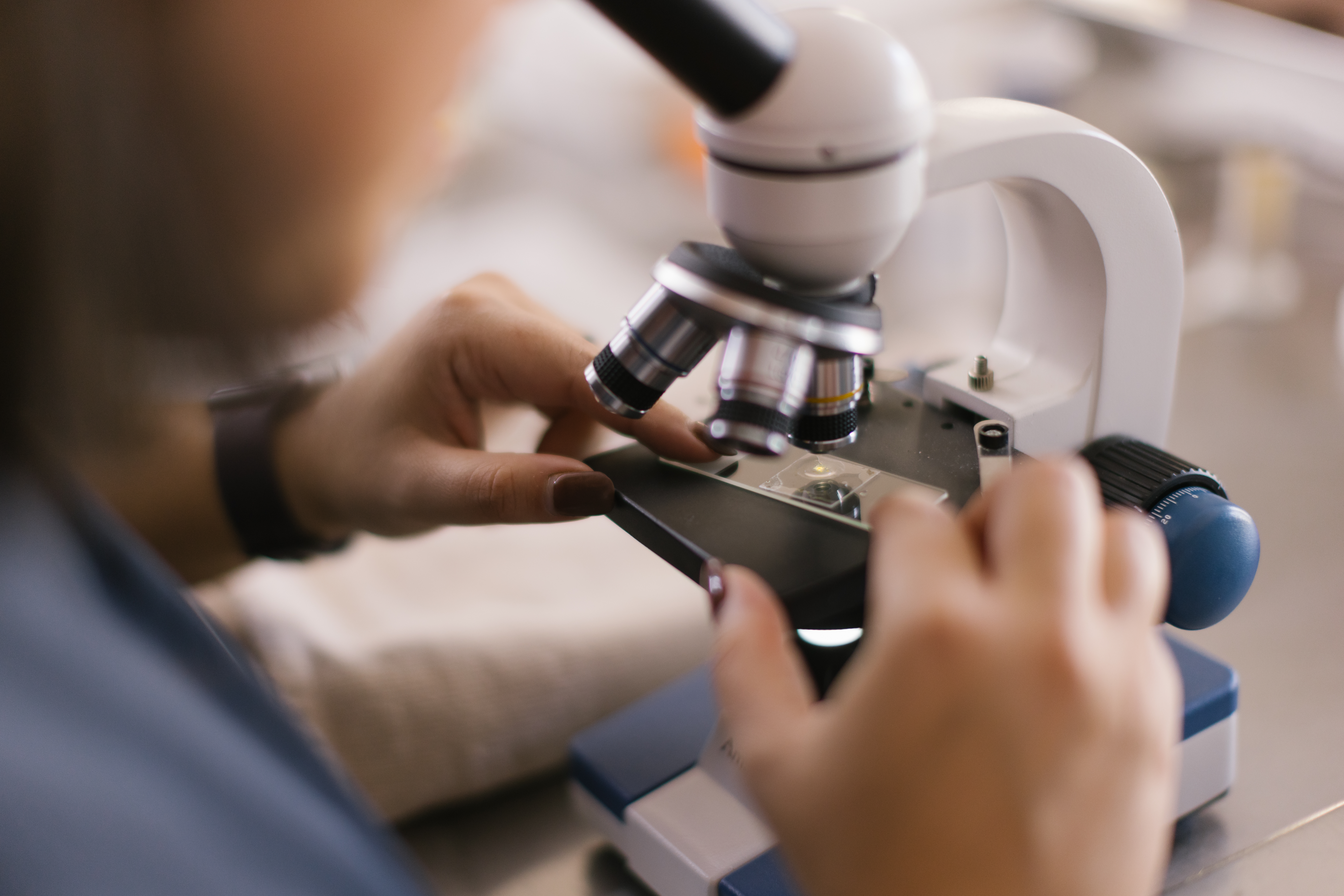 The Clinic To Care Experience - volunteer examinging a sample under a microscope