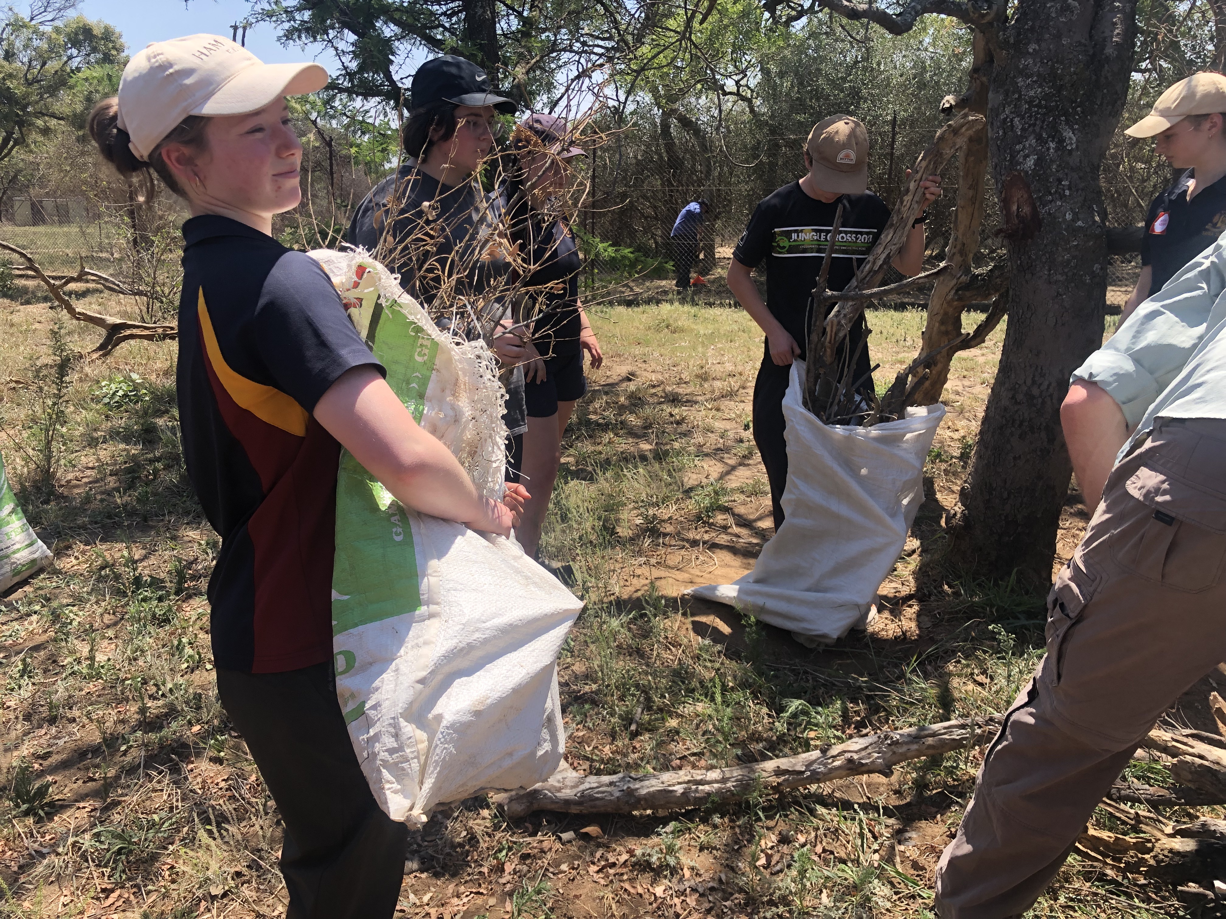Service Learning Field Trip - students carrying bush debris 