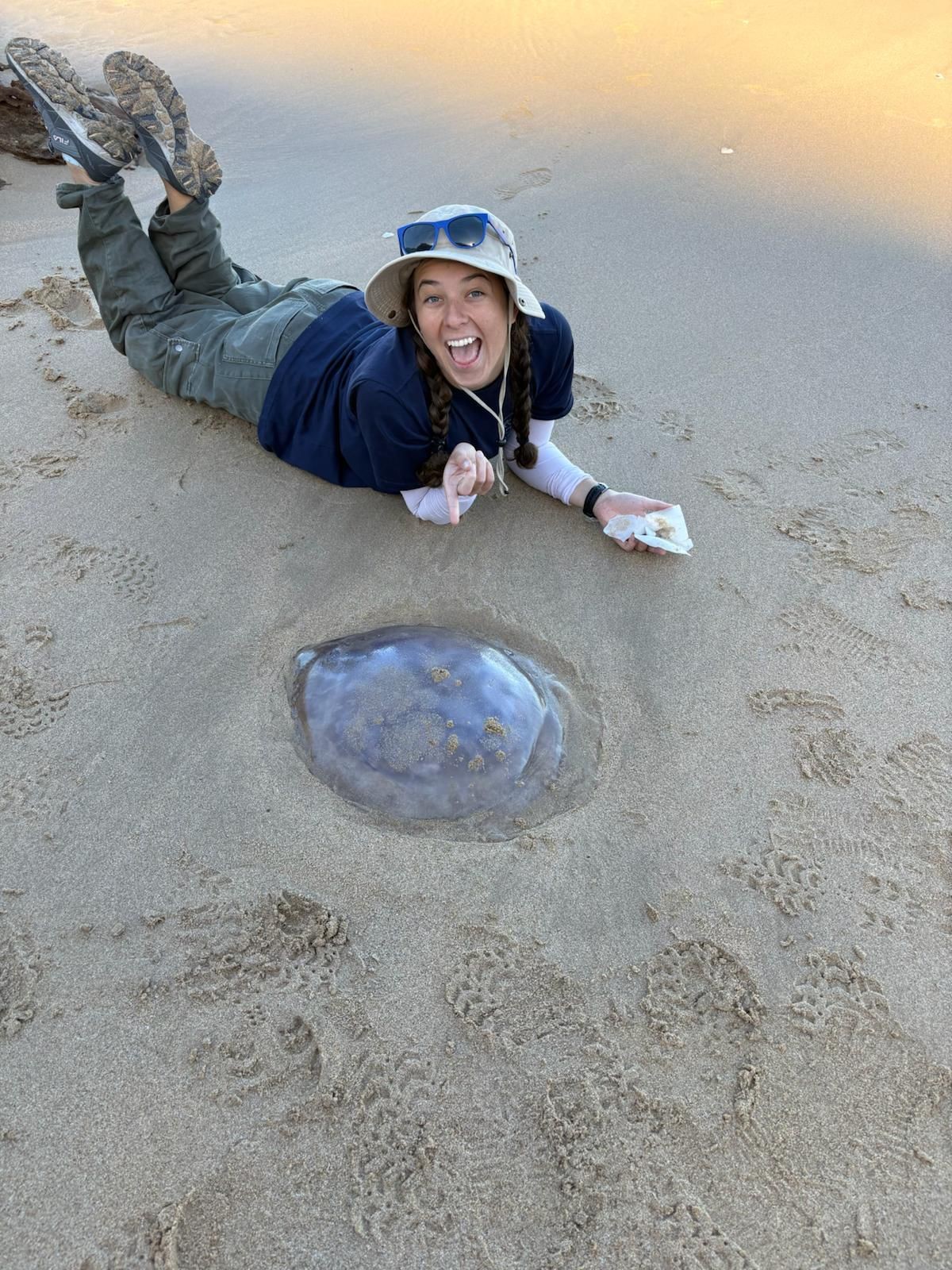 Volunteer posing with jellyfish on beach 