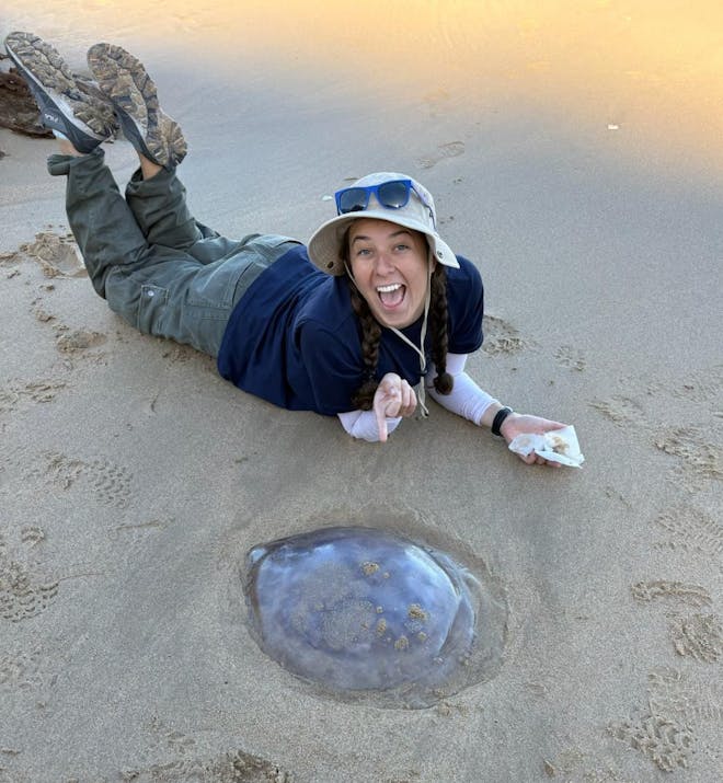 Volunteer posing with jellyfish on beach