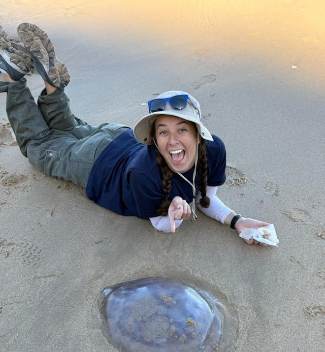 Volunteer Andrea Gomez Jackson poses on the beach with a jellyfish