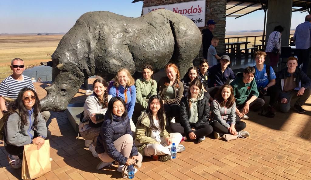Albane Bossuyt: group of studnets poising in front of rihino statue 